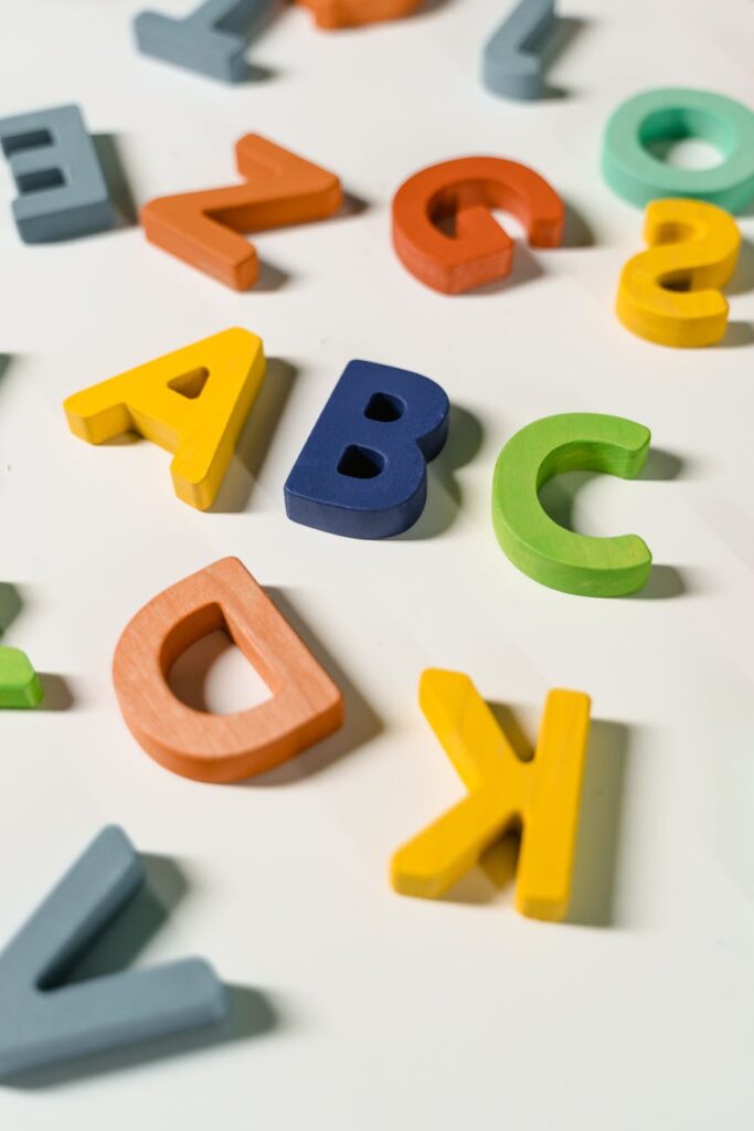 Bright and colorful wooden alphabet letters scattered on a white surface.